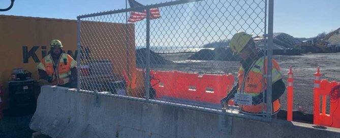 Construction workers assembling barrier fence system in NY