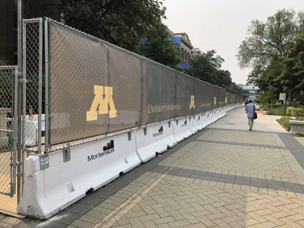 Construction fence lining a pedestrian walkway.