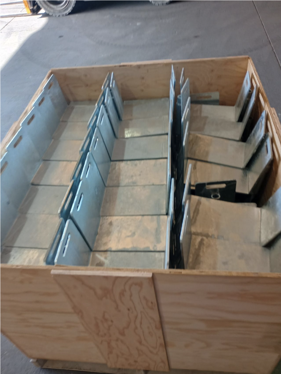 Metal fence base plates organized inside a wooden crate