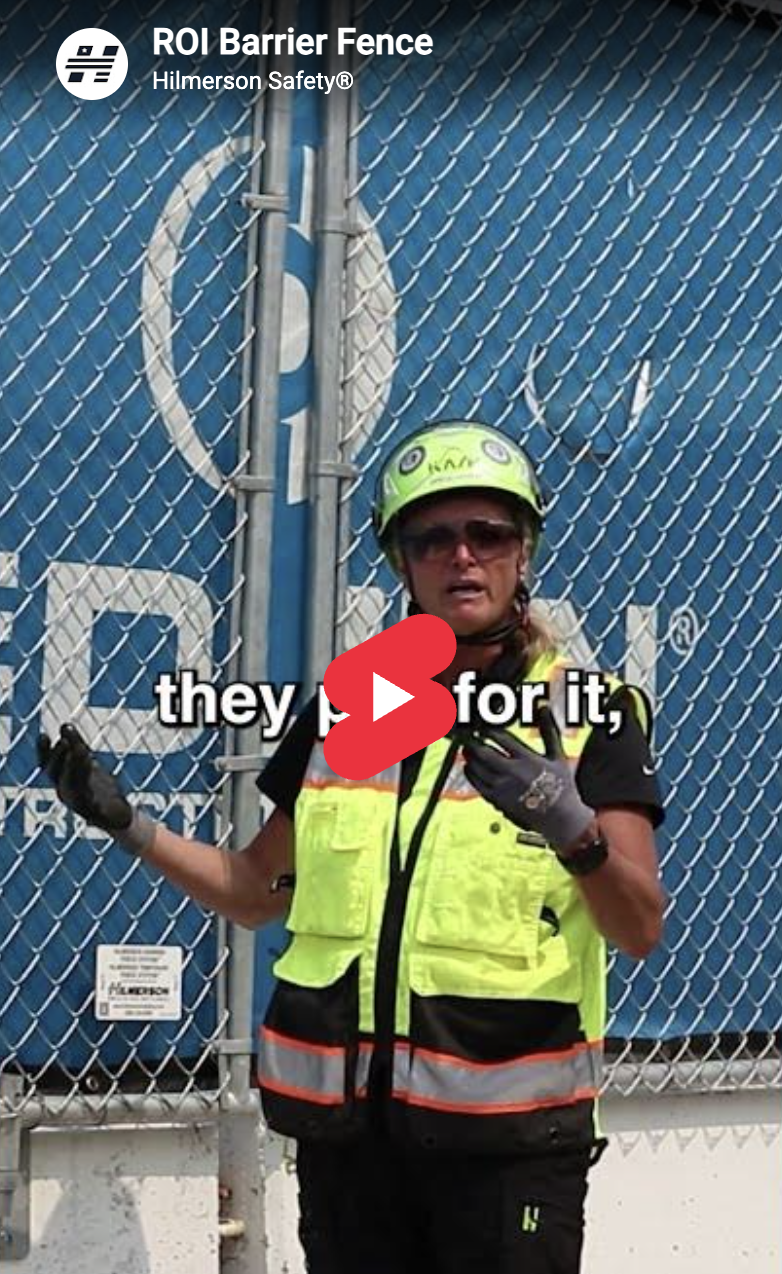 Deb Hilmerson wearing a hard hat and high-visibility safety vest standing in front of a fence.